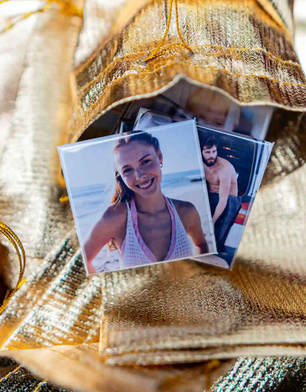 Strahlendes Lächeln auf einem Strandfoto als Magnet – perfekte Sommererinnerungen, verpackt in einem goldenen Säckchen.