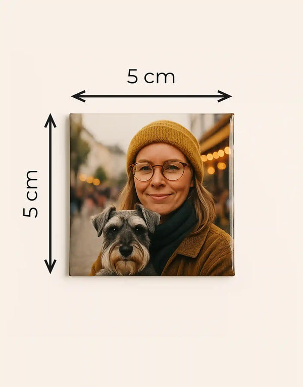 Quadratischer Fotomagnet mit glänzender Oberfläche, 5x5 cm, zeigt eine lächelnde Frau mit Brille und gelber Mütze, die einen kleinen Hund im Arm hält, unscharfer Hintergrund mit Lichtern.